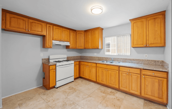 A kitchen with wooden cabinets and a white stove top oven.